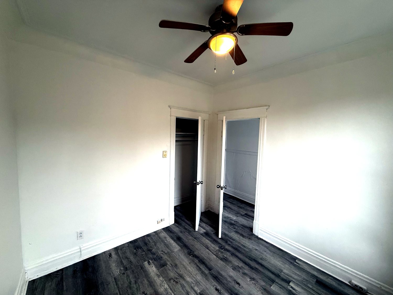 Chambre vide avec placard ouvert et ventilateur de plafond.