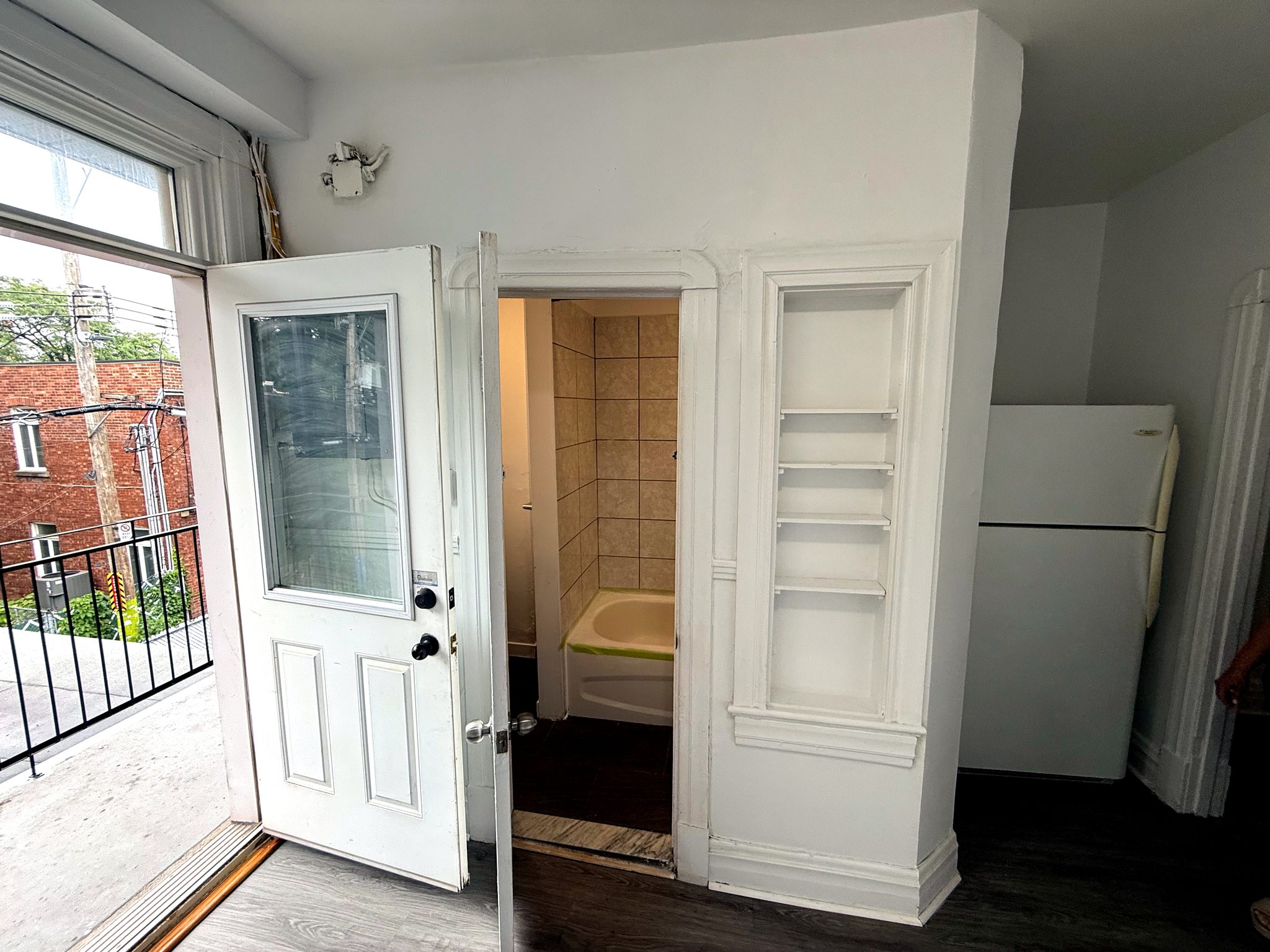 Porte de la salle de bain ouverte sur la baignoire, garde-manger intégré et réfrigérateur.