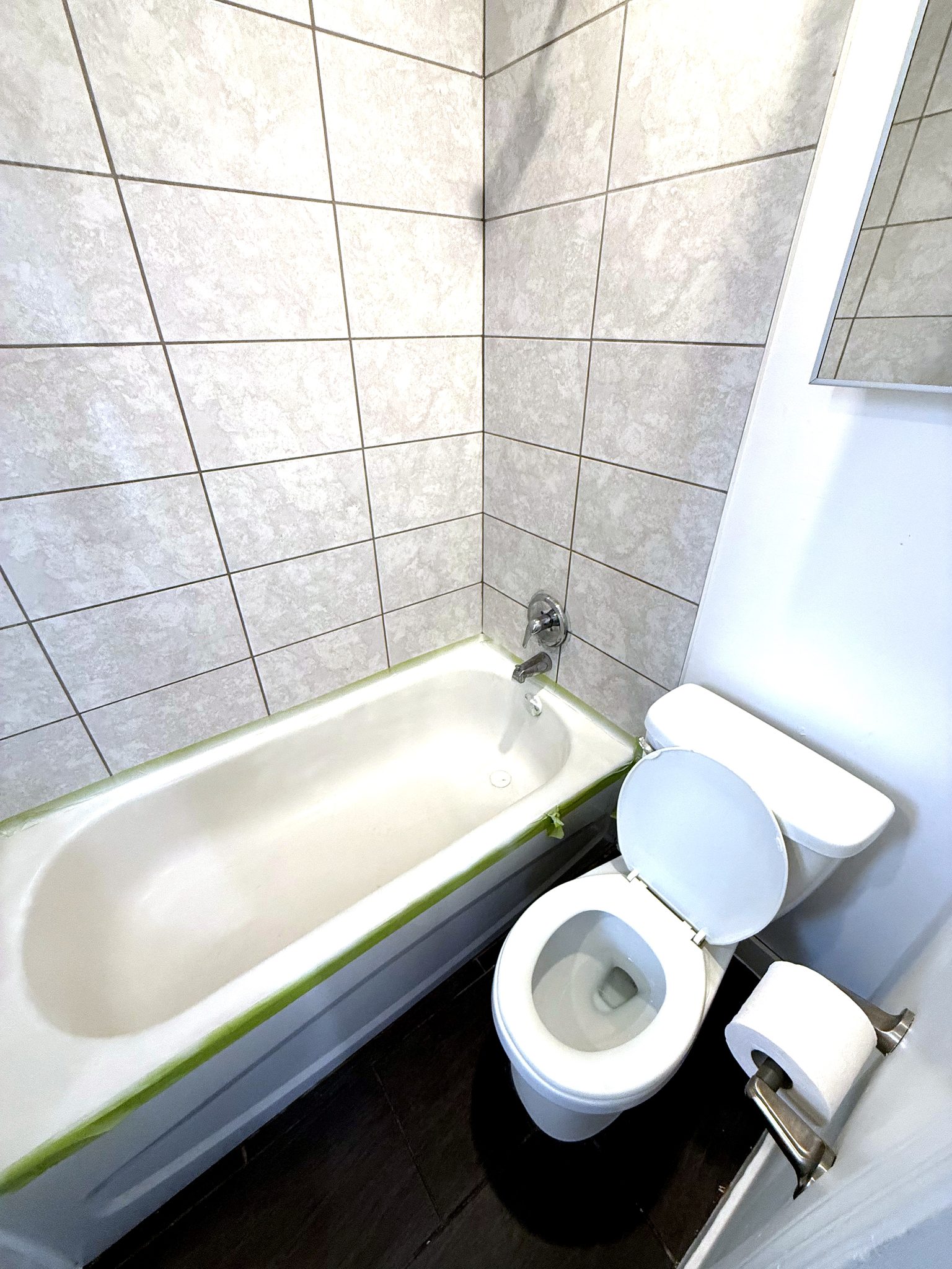 Salle de bain avec baignoire, céramique beige et vanité foncée.