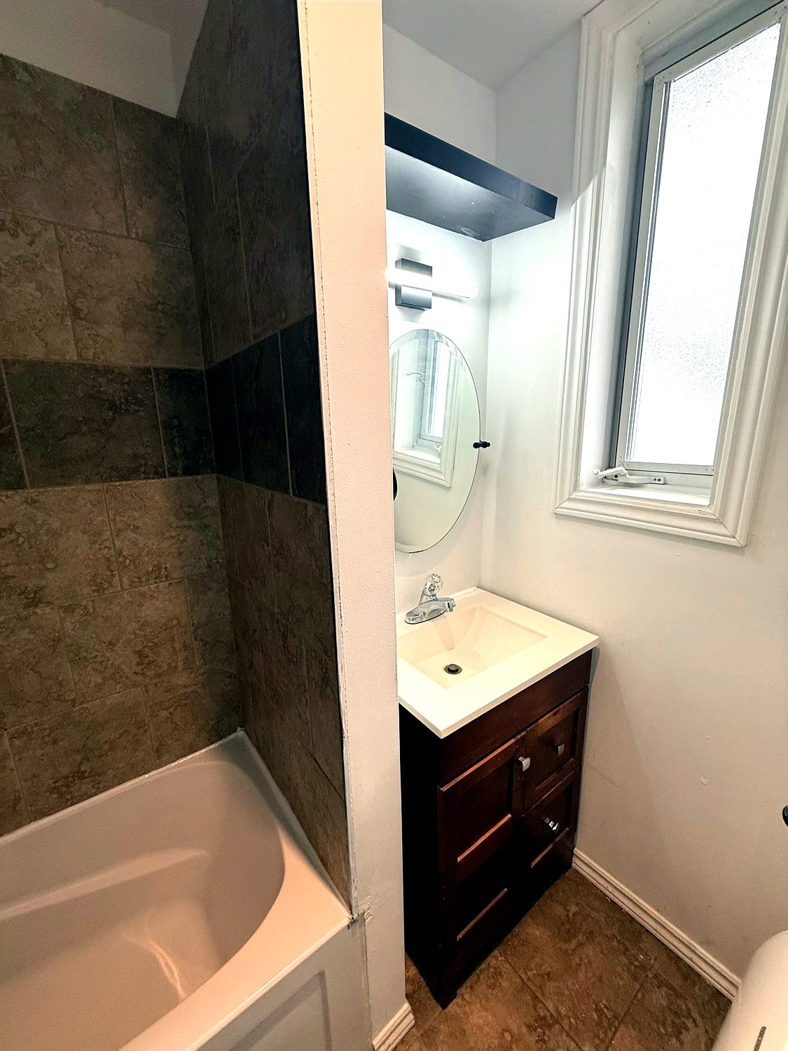Lavabo de la salle de bain, vanité en bois foncé et miroir rond.