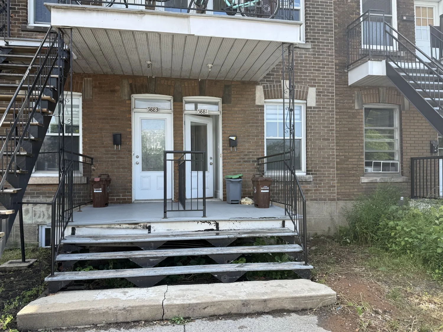 Le triplex vu de la rue, avec les immeubles voisins en brique.